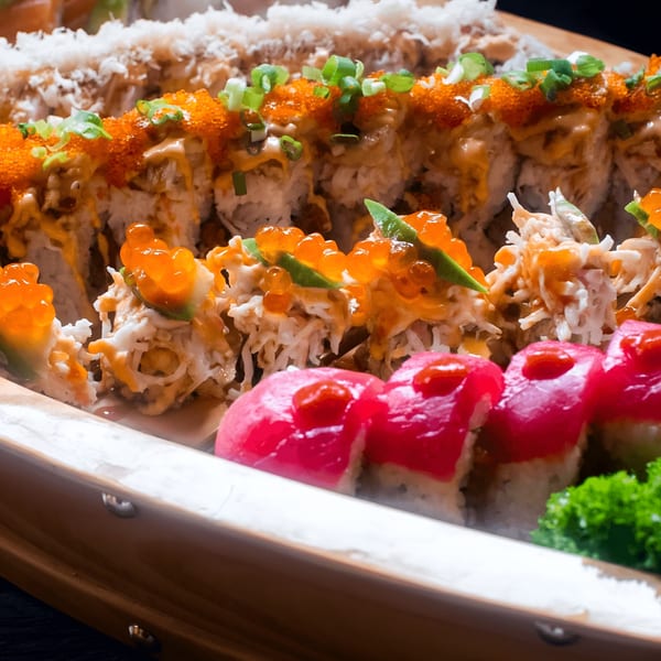 A sushi boat filled with various Kumagoro sushi rolls, including tuna, crab, and roe.