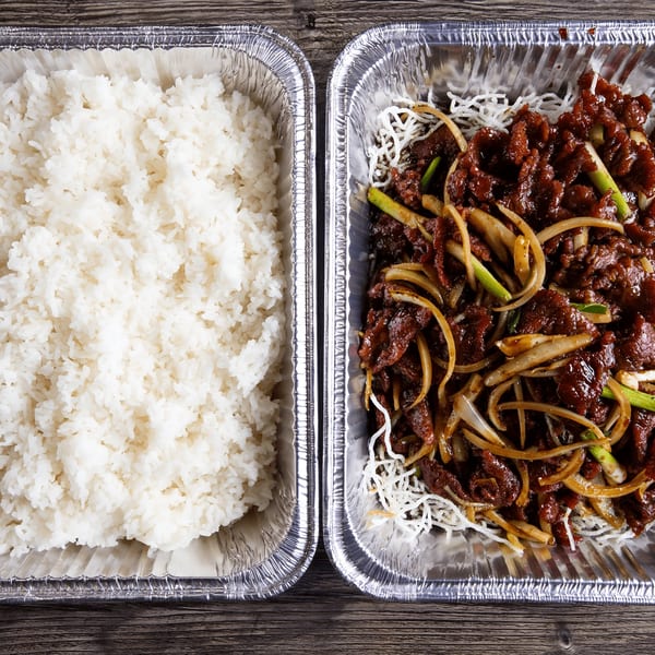 Two foil containers, one with white rice and the other with beef and onions.